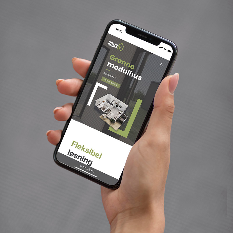 Hånd som holder en mobil, med mockup av webside for Romsly